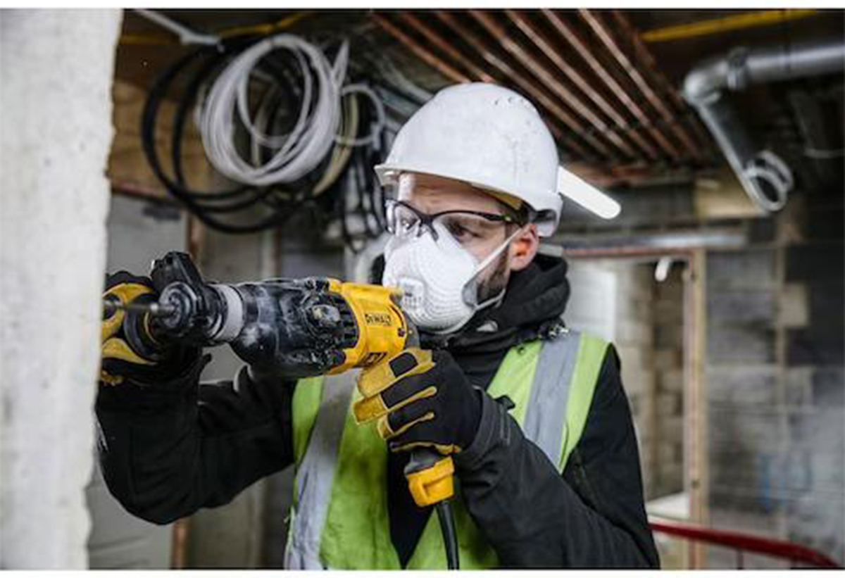 Απεικονίζεται άνδρας με προστατευτική μάσκα και κράνος να χρησιμοποιεί το πιστολέτο σε τοίχο.